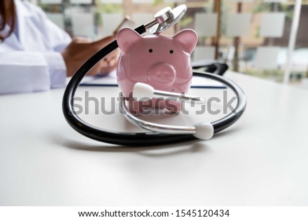 Pink piggy bank with medical equipment on a white table and nurse sitting behind Medical concepts and health insurance.