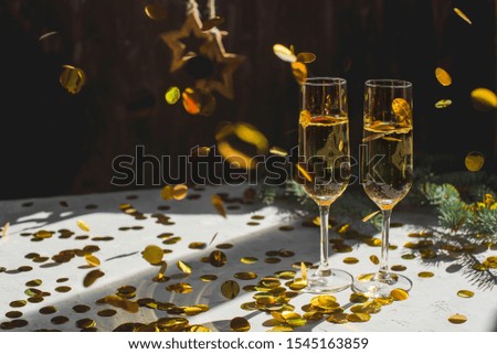 Two glasses of champagne in golden confetti as a symbol of New Year's celebration. Copyspace.