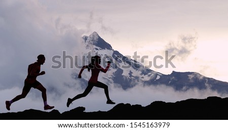 Running people athletes silhouette trail running in mountain summit background. Man and woman on run training outdoors active fit lifestyle.