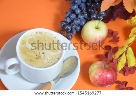 Autumn leaves and hot steaming cup of coffee. Wooden table against golden sunset or sunrise light background. Fall season, leisure time and coffee break concept