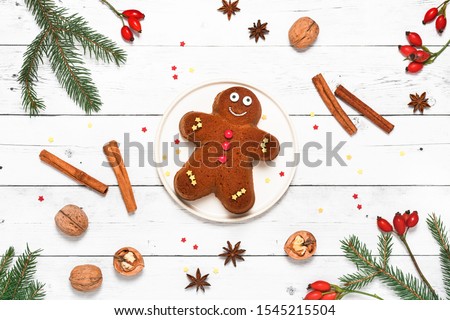 Smiling gingerbread man cake with sugar, spices, cinnamon sticks, star anise and walnuts. Homemade Christmas food concept. Flat lay.