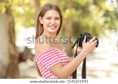 Beautiful female photographer with camera outdoors