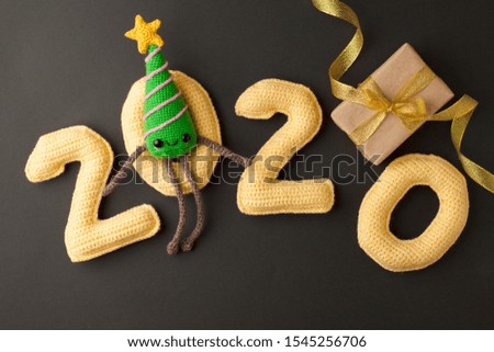 Symbol cute knitted toy Christmas Tree and yellow number 2020 on black background, Happy new year card, kawaii decorative toy, children kids diy funny idea 