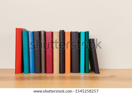 Simple composition of many hardcover books, raw of books on a wooden table and a light background. I'm going back to school. Copy space Education.