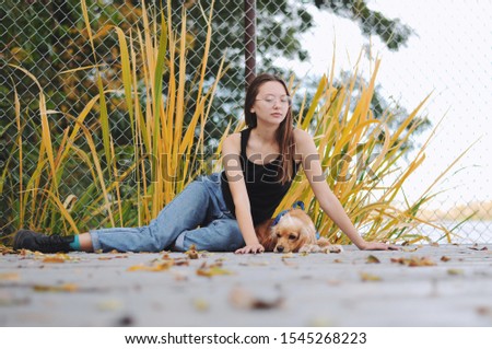 Girl with her dog, English Cocker Spaniel, sitting on the bench near the lake	
