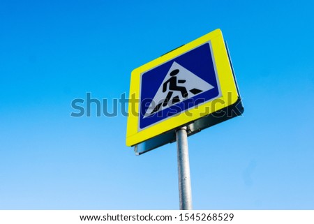 pointer to a pedestrian crossing against the sky in sunlight