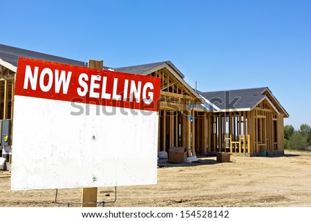 Home is still under construction with a sell sign in the foreground. 