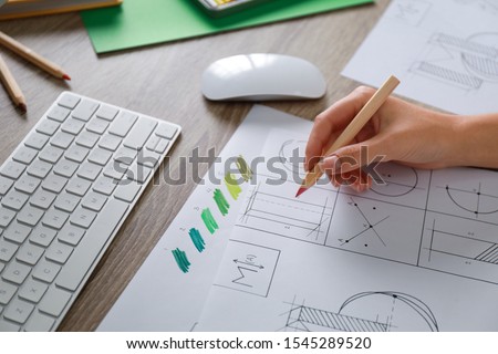 Female designer working at wooden table, closeup
