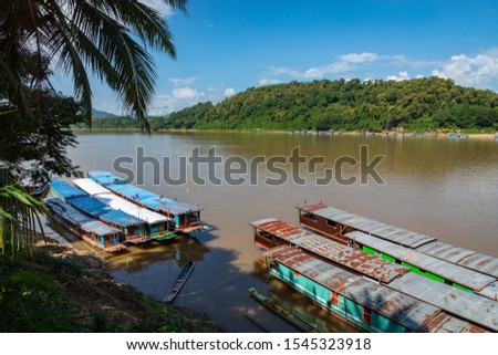 Traditional Long Boat on the Mekong River and mountains view in Luang Prabang, Laos. 