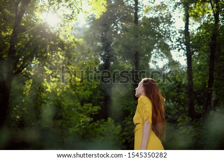 Dreamy And Candid Portrait Of Redhead Young Woman In Park, Looking At Sun With Flare In Background.