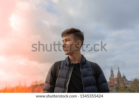 young attractive man stands and smiles against the sunset sky