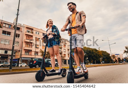 Young couple on vacation having fun driving electric scooter through the city.	 Royalty-Free Stock Photo #1545404642