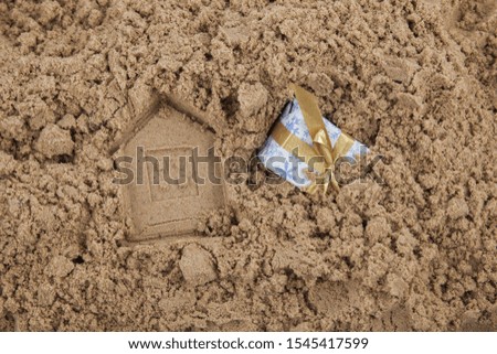 The concept of the imprinted house on sand and a buried gift next to it