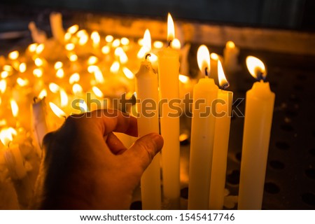 Hand lighting a candle in the church