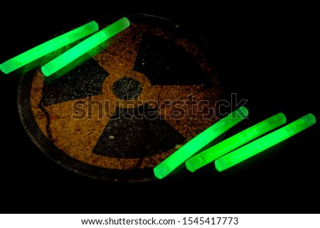 Radioactive matter, hazardous chemical and nuclear energy research conceptual idea with atomic radiation symbol illuminated by bright glow in the dark green uranium sticks on dark background