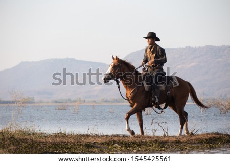 cowboy riding horse in lake against mountain