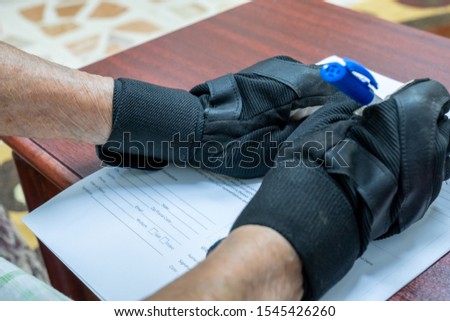 Muslim old woman wearing fingerless gloves and sigining some documents