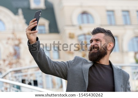 Hi there. Man smiling taking selfie photo smartphone urban background. Streaming online video call. Mobile internet. Hipster mobile phone. Blog content. Personal blog. Modern life. Mobile internet.