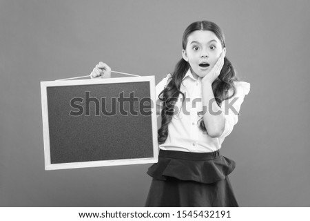 oh my god. surprised pupil in school uniform. copy space. commercial marketing conept. business school advert. new shopping idea. school market sales. signage. surprised school girl with blackboard.