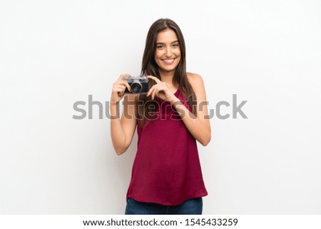 Young woman over isolated white background holding a camera