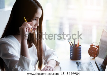 asian girl holding pencil on her head while thinking.