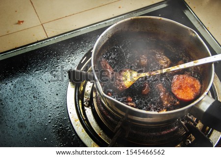 Burned food in the pot on a gas stove and full of oil stains from warming up food that is forgetful. Royalty-Free Stock Photo #1545466562