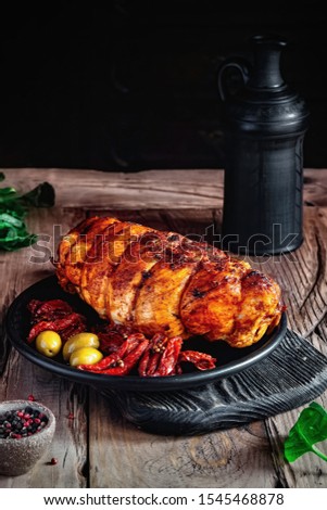 Roasted turkey breast on a black plate with sun-dried tomatoes. Dark style photo on rustic background.