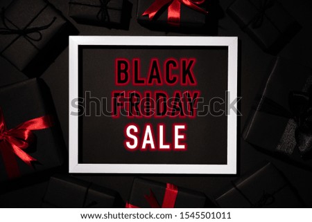 Top view of Black Friday Sale text on white picture frame with black gift box red ribbon and Christmas ball. Shopping concept and black Friday composition.