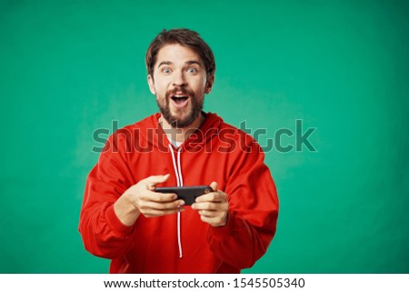 Emotional man in a red sweater with mobile phone on a green background