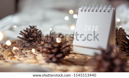 New Year 2020 grey calendar with lights on rustic server with cones and wooden Christmas tree toys