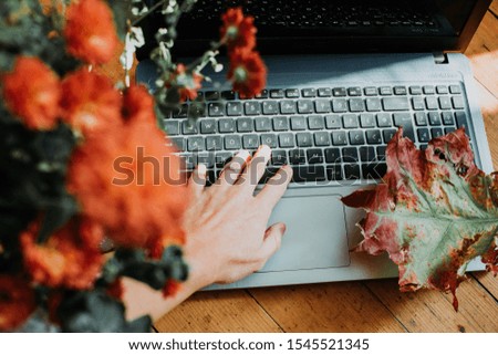 Close up woman hand on laptop and flowers behind
