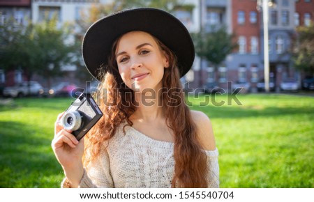 Lifestyle portrait of stylish girl with retro camera during walk in city street
