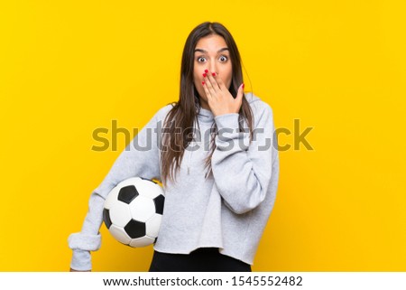 Young football player woman over isolated yellow background with surprise facial expression