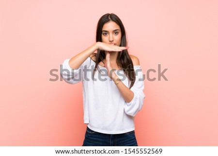 Young woman over isolated pink background making time out gesture
