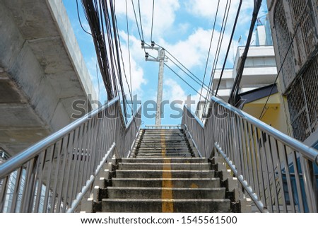 Close up concrete steps of under construction pedestrian bridge with electric wires, cables and overhead electric pole Royalty-Free Stock Photo #1545561500