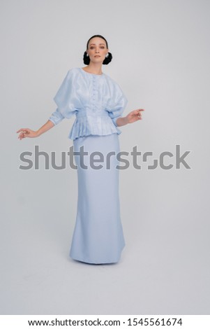 Beautiful caucassian model wearing Asian traditional dress for Muslim woman isolated over white background.Eid ul fitr fashion and beauty.