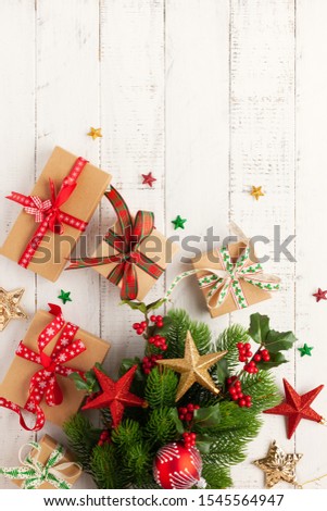 Christmas background with gift boxes, Christmas decorations and branches of holly and fir on white wooden background. Winter festive concept. Flat lay, copy space.