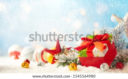 Christmas winter background with gift box, Christmas baubles and fir tree branches on snow.