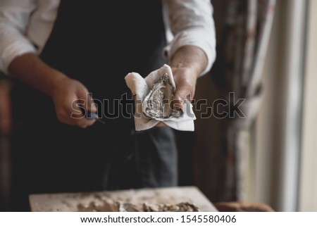 The process of opening oysters, a knife for oysters, male hands open oysters Royalty-Free Stock Photo #1545580406