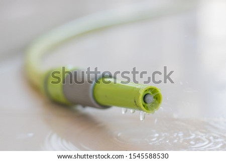 The green water hose has the water being dispersing.
