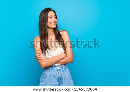 Young woman over isolated blue background happy and smiling