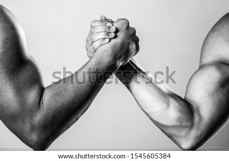Muscular men measuring forces, arms. Hand wrestling, compete. Hands or arms of man. Muscular hand. Two men arm wrestling. Rivalry, closeup of male arm wrestling. Black and white.