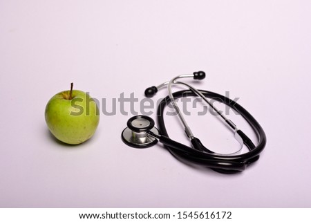 Green apple and stethoscope isolated on grey background