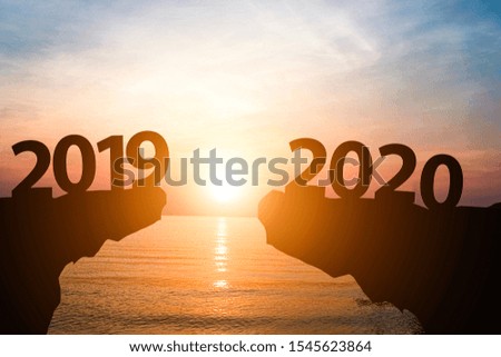 Silhouette of year 2019 to 2020 with sun rise on mountain and sea. Starting of new year concept. (defocused)