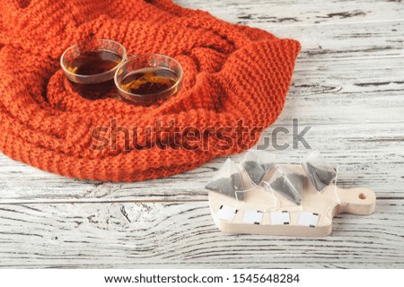 Tea in tea bags close-up and copy space. The concept of autumn, warmth, disease. Two cups of tea in a textured scarf