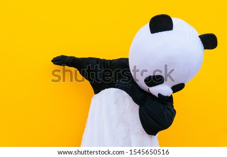 Person with panda costume dancing dab dance. Mascot character lifestyle concept on colored background Royalty-Free Stock Photo #1545650516