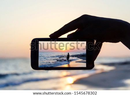 Man takes a sunset photo with another girl on the mobile phone