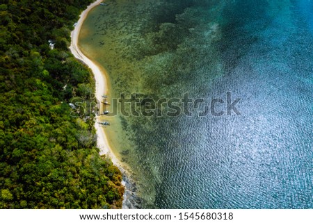 Palawan, Philippines, El Nido. Aerial drone above view of a secluded deserted tropical beach with local traditional boats on coastline in front of rainforest jungle