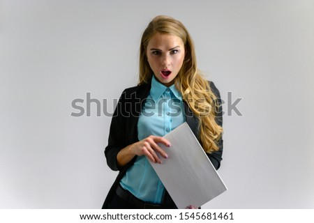 Portrait of a pretty blonde girl financial secretary with long curly hair in a business suit standing in the studio on a white background with emotions in different poses with a folder in hands.