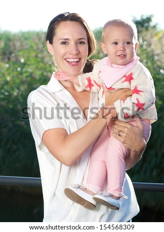 Portrait of a happy mother holding beautiful baby outdoors
